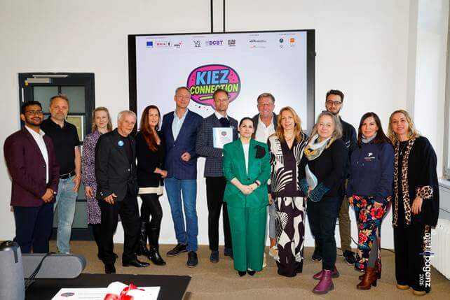 Das Kiez-Connection-Team mit Vertreter:innen der zentralen Partnerinstitutionen bei der Vorstellung des Modellkonzepts vom World Cleanup Institute und der Übergabe des Wertgutscheins an SchutzengelWerk e.V. Berlin am BCBT-Campus im CIC, 30. April 2026. (v.l.n.r.) M. Naik, T. Rupp, M. Raisma, A. Moor, D. Schwerdt, H. Holland, M. Peuckert, M. Baum, S. Ober, Y. Martini, BBWA, P. Kalus, M. Albarracin