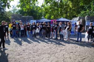 Eine große Gruppe in World-Cleanup-Day-Shirts mit Säcken steht vor Pavillons und Graffiti-Felsen im Park.