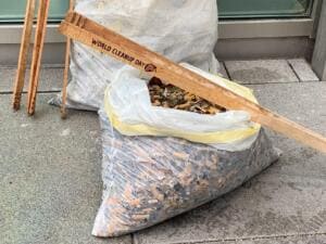 Ein durchsichtiger Sack ist bis oben mit Zigarettenkippen gefüllt, darüber liegt ein Holzstab mit der Aufschrift „World Cleanup Day“.
