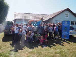 Eine große Gruppe aus Erwachsenen und Kindern steht vor einem Vereinsheim auf einer Wiese neben einem Roll-up von „Let's do it! Thüringen“.
