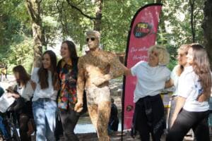 Eine Gruppe junger Frauen posiert lachend um die Skulptur aus Zigarettenstummeln vor einer World-Cleanup-Day-Beachflag.