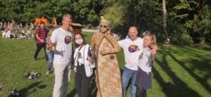Vier Erwachsene in World-Cleanup-Day-Shirts stehen auf einer Wiese im Englischen Garten neben der Skulptur aus Zigarettenstummeln.
