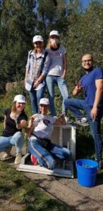 Fünf Erwachsene, einige mit weißen Kappen, posieren auf einer Böschung mit einem großen weißen Fundstück und einem blauen Eimer.