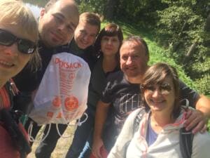 Selfie einer lachenden Gruppe Erwachsener, einer hält einen Beutel mit gesammeltem Müll.