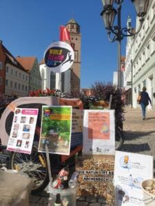 Auf einem Lastenrad in der Donauwörther Altstadt stehen Infoplakate, ein World-Cleanup-Day-Schild und ein Behälter mit gesammelten Zigarettenstummeln, dahinter das Liebfrauenmünster.