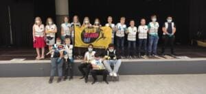 Eine Schulklasse in World-Cleanup-Day-Warnwesten steht und sitzt mit einer gelben World-Cleanup-Day-Fahne auf einer Bühne.