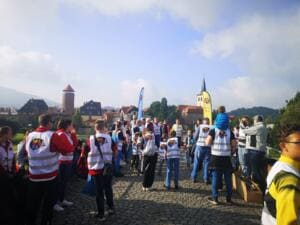 Viele Menschen in World-Cleanup-Day-Westen versammeln sich auf einem Kopfsteinpflasterplatz an der Werra, im Hintergrund Burgturm und Kirchturm.