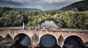 Luftaufnahme einer Menschenmenge auf einer steinernen Bogenbrücke über die Werra zwischen grünen Hügeln.