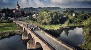 Luftaufnahme einer langen Steinbogenbrücke über die Werra, auf der sich eine große Menschengruppe versammelt hat, im Hintergrund ein Ort mit Kirchturm.