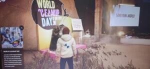 Bildschirmfoto einer virtuellen 3D-Welt: Eine Spielfigur steht vor einer großen World-Cleanup-Day-Kulisse mit dem Datum 17. September 2022.