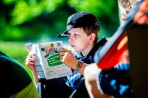 Ein Junge mit Kappe liest konzentriert eine Broschüre mit dem Titel World Cleanup Day macht Schule.