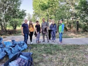 Sieben Erwachsene stehen auf einem Feldweg, im Vordergrund liegen zahlreiche volle blaue Müllsäcke und ein Bollerwagen.