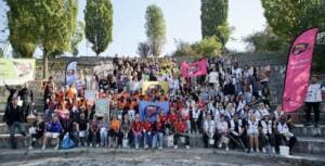 Großes Gruppenfoto: Hunderte Teilnehmende sitzen und stehen auf den Stufen des Mauerpark-Amphitheaters, mit Fahnen, Beachflags und World-Cleanup-Day-Bannern.