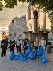 Sieben Frauen mit Holzgreifzangen stehen vor der Nikolaikirche in Berlin hinter mehreren gefüllten blauen Müllsäcken.