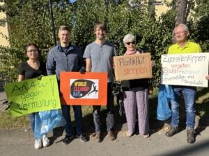 Fünf Erwachsene halten selbstgemalte Schilder mit Aufschriften wie Plastikflut stoppen und Zigarettenkippen vergiften Boden und Wasser sowie ein World-Cleanup-Day-Schild.